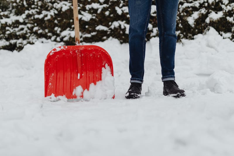 A residential driveway cleared to the pavement with snow banked along both edges